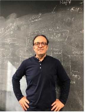 George Em Karniadakis stands in front of a chalkboard