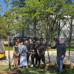 People pose near a newly planted tree.
