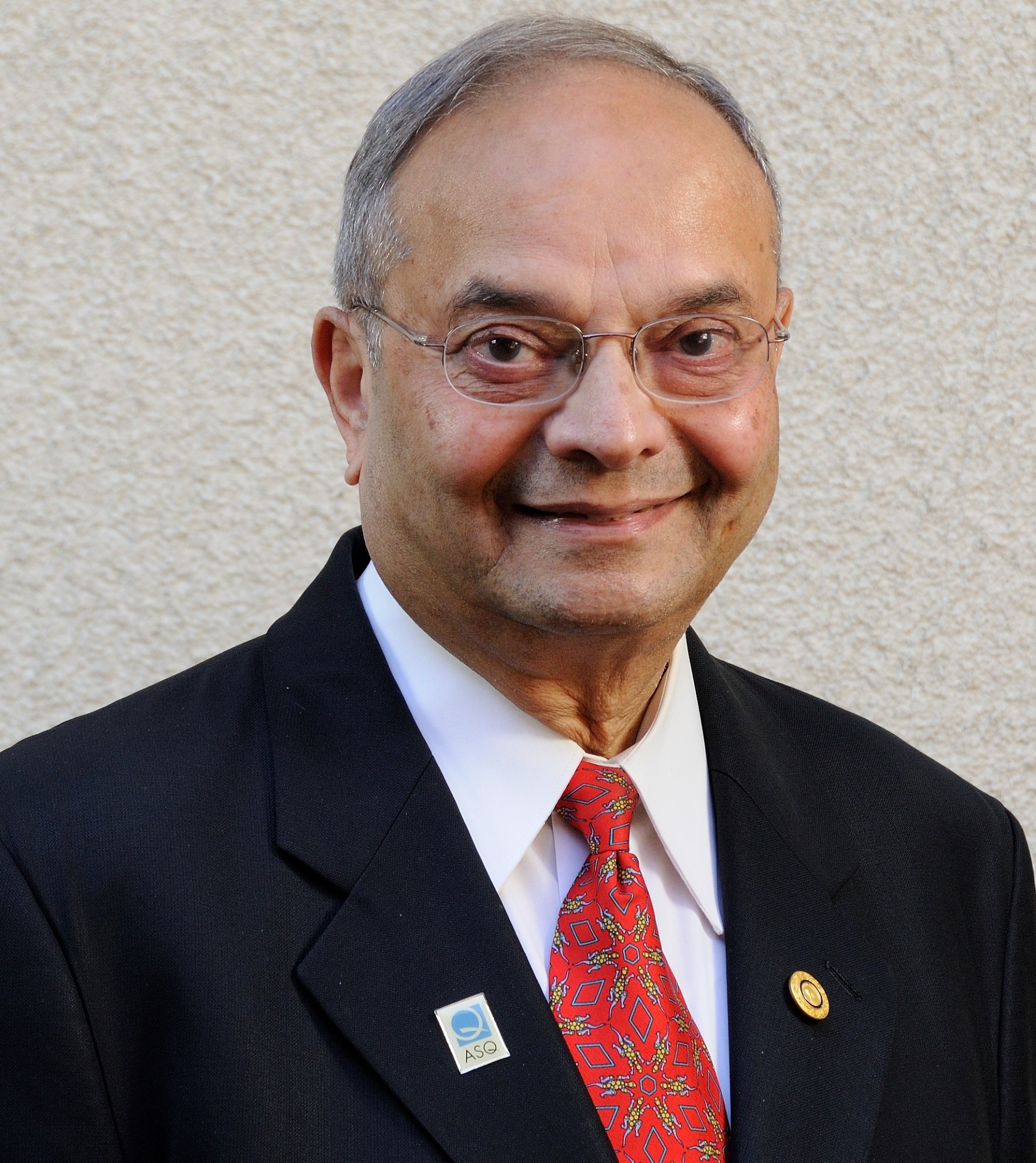 A man in a suit and tie smiles in a headshot.