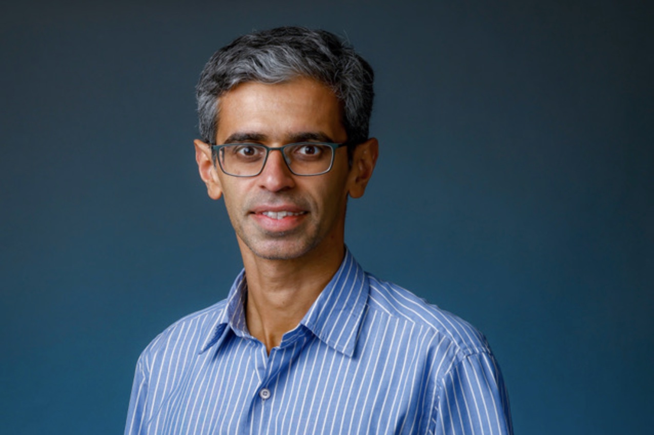 A man wearing a blue striped search smiles in a portrait.